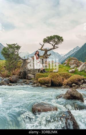 Asian female traveler in traditional dress by flowing river with iconic ...