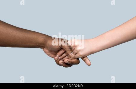 Caucasian woman and African-American man holding hands together. Racism concept. Giving a helping hand to another. Woman and african woman hand. Hands Stock Photo