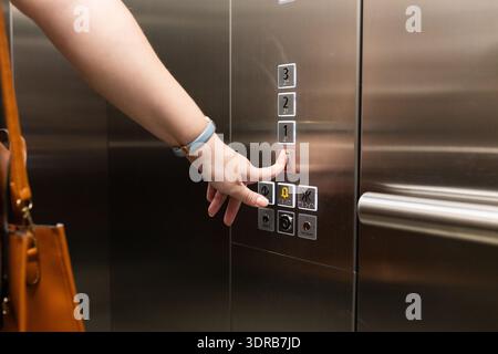 Pressing elevator button, person with handbag using elevator in office building Stock Photo