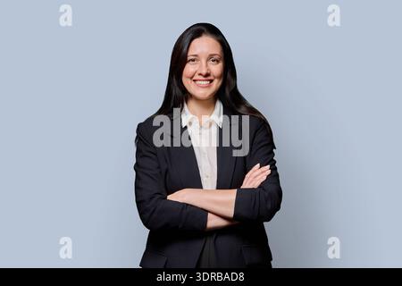 Confident successful middle-aged businesswoman in black jacket on grey studio background Stock Photo