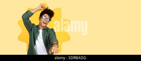 Happy Young Man Dancing in Front of a Yellow Background During a Fun Moment Stock Photo