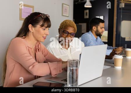 Collaborating on project, diverse team using laptop and smartphone in office Stock Photo
