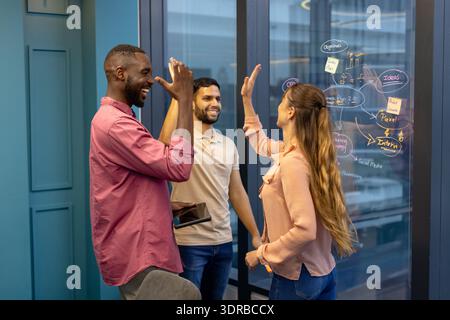 High-fiving, diverse colleagues celebrating successful project in office Stock Photo