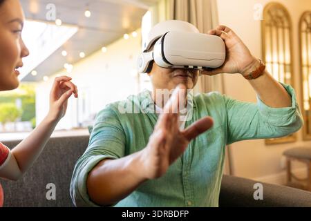 Using VR headset, father exploring virtual reality while daughter guiding him Stock Photo