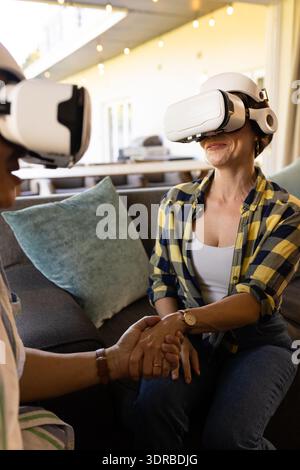 Using VR headsets, couple holding hands and enjoying virtual reality experience Stock Photo