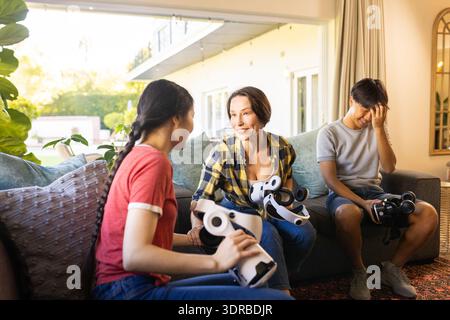 Using VR headsets, family enjoying virtual reality experience together at home Stock Photo