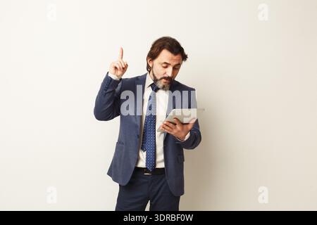 Businessman Holding Tablet in Office Setting While Presenting Ideas to Audience Stock Photo