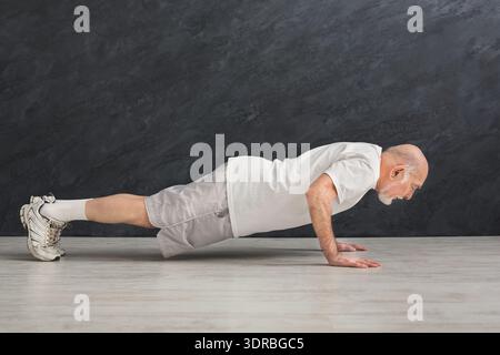 Senior Man Doing Push-Ups in Home Workout Setting During the Day Stock Photo