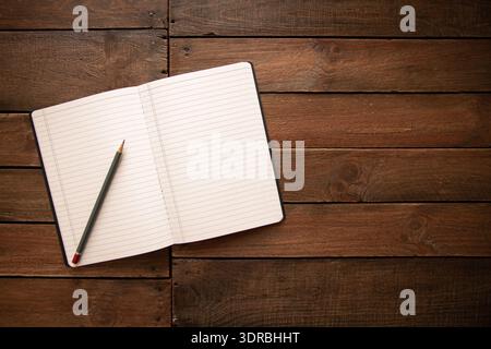 Open notebook and pencil on a rustic wooden board Stock Photo