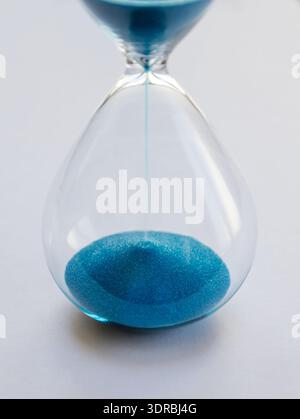 Hourglass containing blue sand isolated on white background Stock Photo