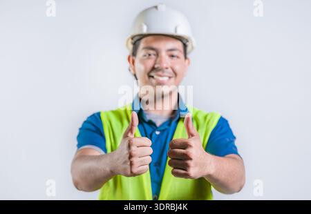 Smiling latin engineer geesturing ok isolated. Positive male engineer with thumbs up, isolated Stock Photo