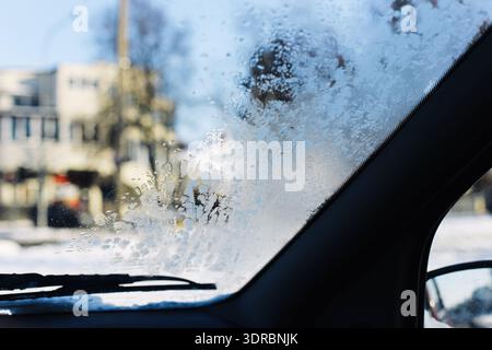 Frozen car windshield during winter morning. Ice and condensation on vehicle window. Cold weather transportation concept outdoors. Stock Photo