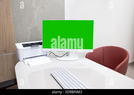 Computer monitor with green screen in modern office interior. Workspace mockup and chroma key display concept on clean desk. Stock Photo