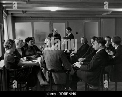 Students from the Amsterdam film school are engaged in discussion during a coffee break in 1936. The photograph highlights informal student interaction, collaboration, and peer exchange outside of formal lessons. This reflects the social aspects of historical Dutch film education and the role of discussion in creative arts learning. Stock Photo