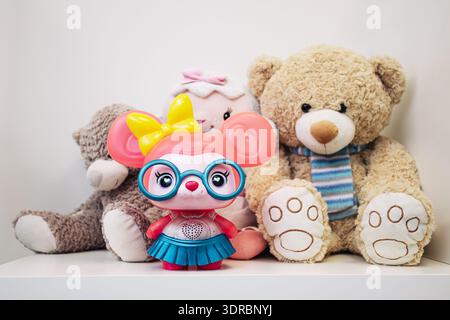 Teddy bears and colorful toy figure on shelf closeup. Childhood, playroom and cute stuffed animal collection indoors at home. Stock Photo