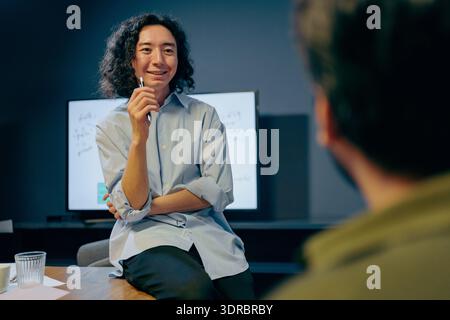 enthusiastic asian creative director engaging in collaborative design discussion at workspace Stock Photo