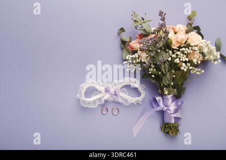 Collection of Wedding Items Including a Bouquet, Rings, and Garter Displayed on Purple Background Stock Photo