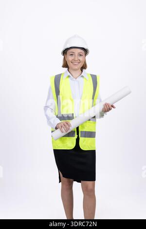 Young female engineer standing with blueprints in uniform Stock Photo