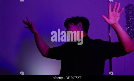 Young man dancing in a room with purple neon lighting Stock Photo