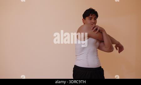 Young man in white t-shirt stretching his arms in studio Stock Photo