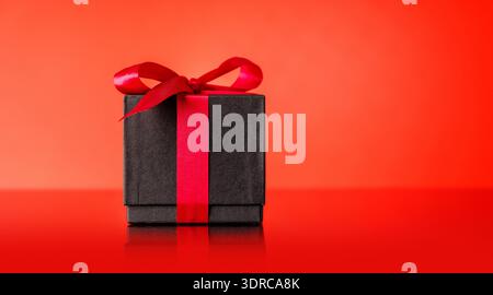 A black gift box adorned with a vibrant red bow Stock Photo