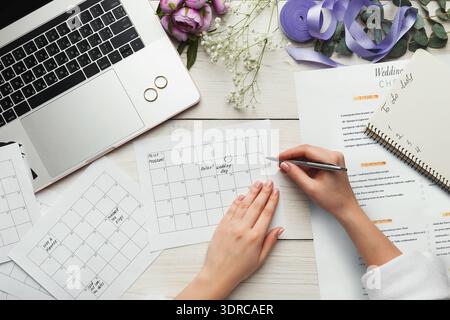 Planning a Wedding With a Calendar, Papers, and Laptop on a Wooden Table With Flowers Nearby Stock Photo