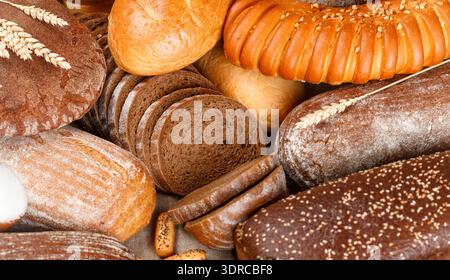Freshly baked rye and wheat bread on the table. Whole and sliced loaves Stock Photo