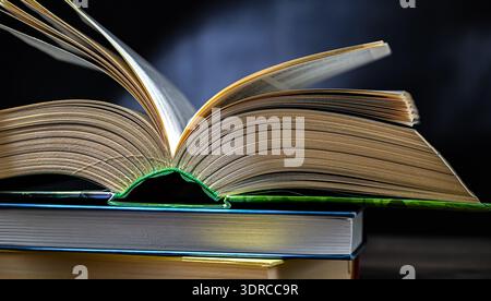 An open book lying on a stack of other books. Stock Photo