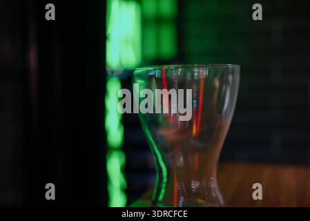 Two modern glass hookahs on a wooden stand in a dark interior with neon lighting.Professional hookahs assembled against a brick wall and green neon in Stock Photo