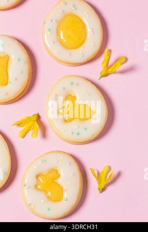 Easter egg cookies with lemon orange curd, covered with white icing and forsythia flowers. Stock Photo