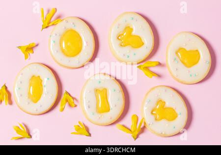 Easter egg cookies with lemon orange curd, covered with white icing and forsythia flowers. Stock Photo