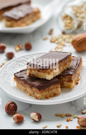Homemade Vegan cocoa dates chocolate bars with coconut, hazelnuts, walnuts and sunflower seeds on a white background. Healthy de Stock Photo