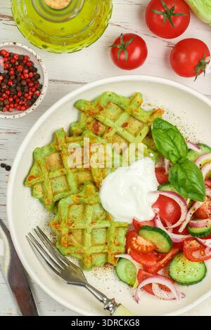 Delicious healthy green waffles with zucchini, spinach and Basil. It is served with a salad of fresh vegetables-tomatoes, cucumb Stock Photo