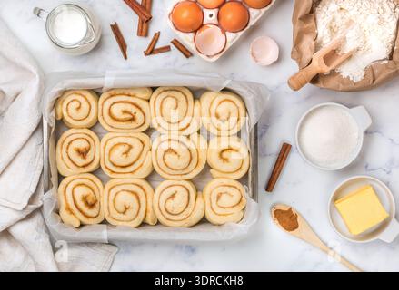 Cinnamon rolls or cinnabon handmade raw dough preparation with spices and sugar filling in a baking dish. Sweet Homemade Pastry. Stock Photo