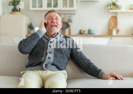 Happy middle aged senior man talking on smartphone with family friends. Older mature grandfather with cell phone talking with gr Stock Photo