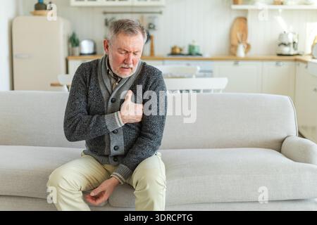 Pain on heart, heart attack. Unhappy middle aged senior man suffering from chest pain heart attack problems with health at home. Stock Photo