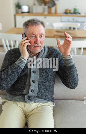 Happy middle aged senior man talking on smartphone with family friends. Older mature grandfather with cell phone talking with gr Stock Photo