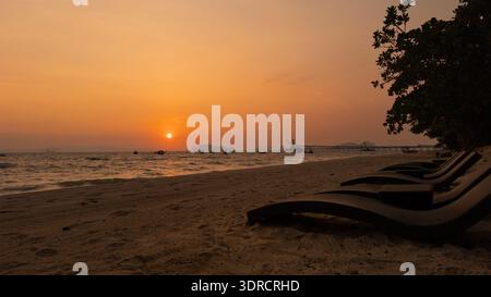 Serene beach scene with boats in dark silhouette against a glowing sunset horizon. Perfect for travel, nature, coastal lifestyle, and peaceful evening Stock Photo