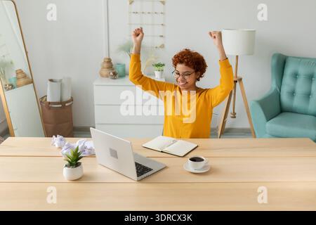 Excited happy african american woman winner. Girl female student looking at laptop passed exam reading great news getting good r Stock Photo