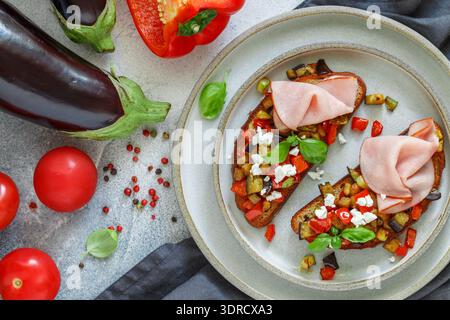 Bruschetta with grilled eggplant, zucchini, tomatoes, onion, garlic, bell pepper, feta cheese, basil Stock Photo