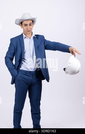 Architect in a suit holding a hard hat and blueprints Stock Photo