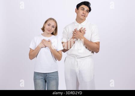 Young couple in white t-shirts making heart shape with hands Stock Photo