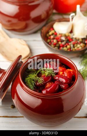 Stewed red beans with tomatoes and garlic in a ceramic pot. Vegetarian dish Stock Photo