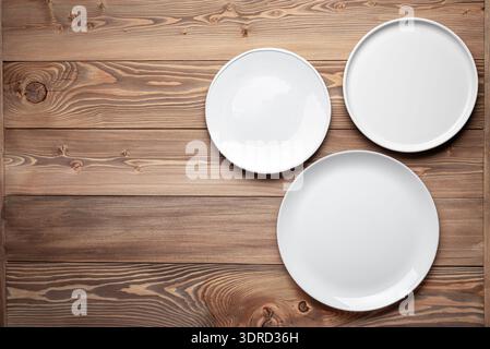 Three empty white plates on wooden table background Stock Photo