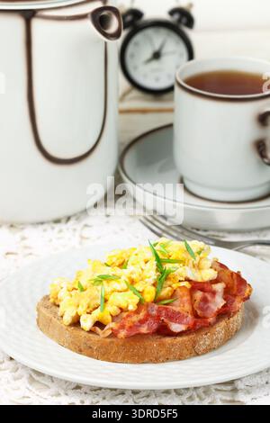 Bread toast with scrambled eggs, fried bacon and green onions Stock Photo