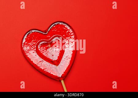 Heart-shaped lollipop on a vibrant red background Stock Photo