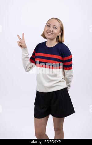 Woman in striped sweater showing victory sign with both hands Stock Photo