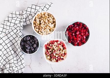 Assorted frozen red, white and black berries in bowls on table top view Stock Photo