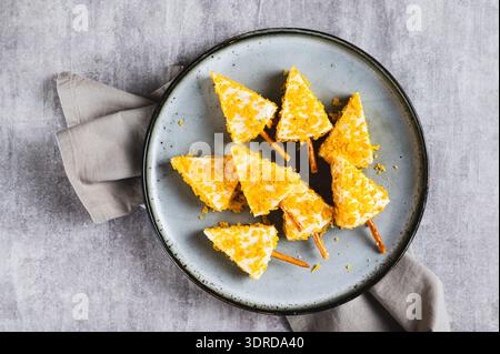 Close up of Christmas trees made from triangle cheese in nacho crumbles on a plate top view Stock Photo