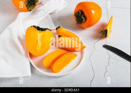 Plate with pieces of sweet tasty persimmon on white background Stock Photo